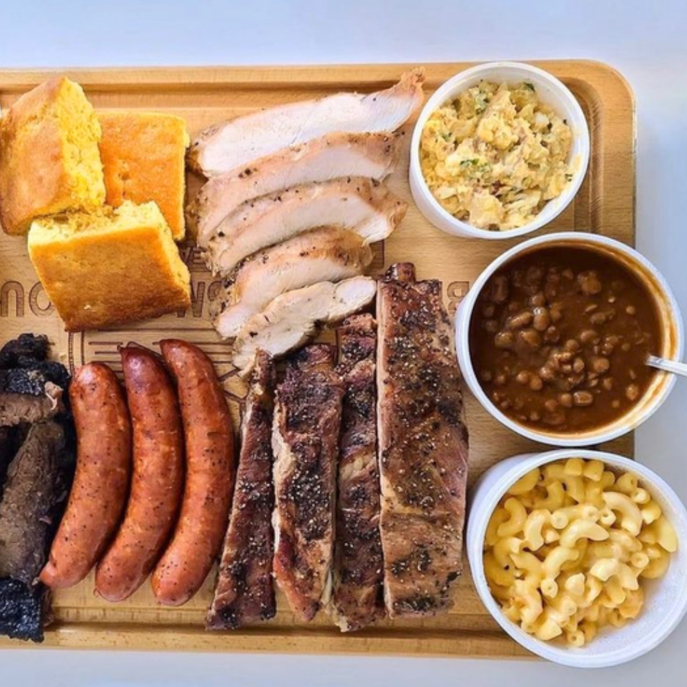 A spread of BBQ items on a wooden board.