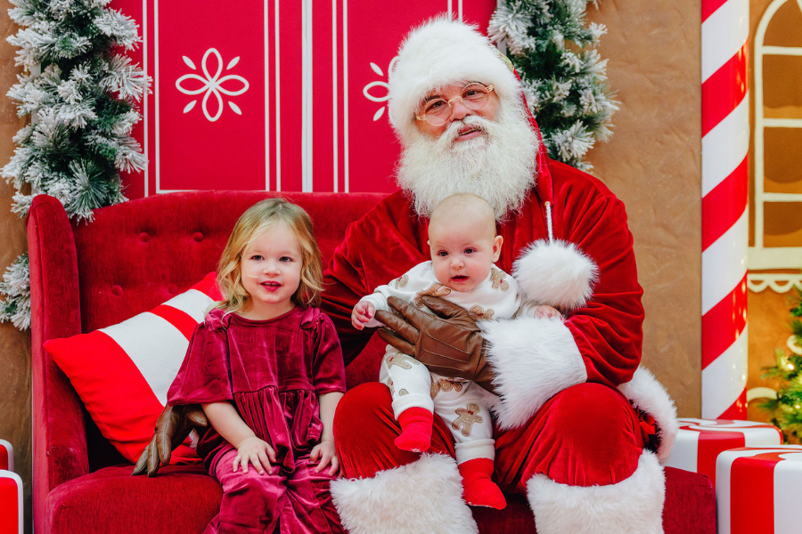 Santa posing for a photo with a young girl and a baby