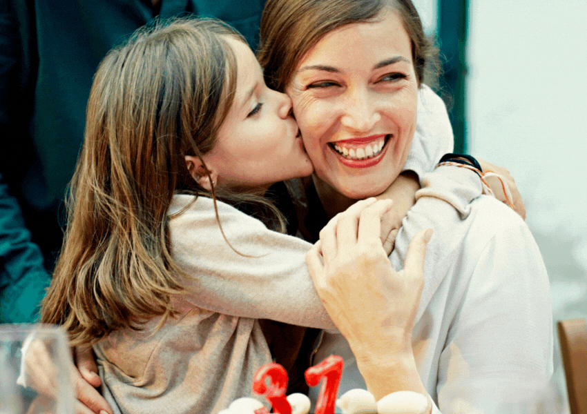 A daughter kissing her mother on her cheek for her birthday.